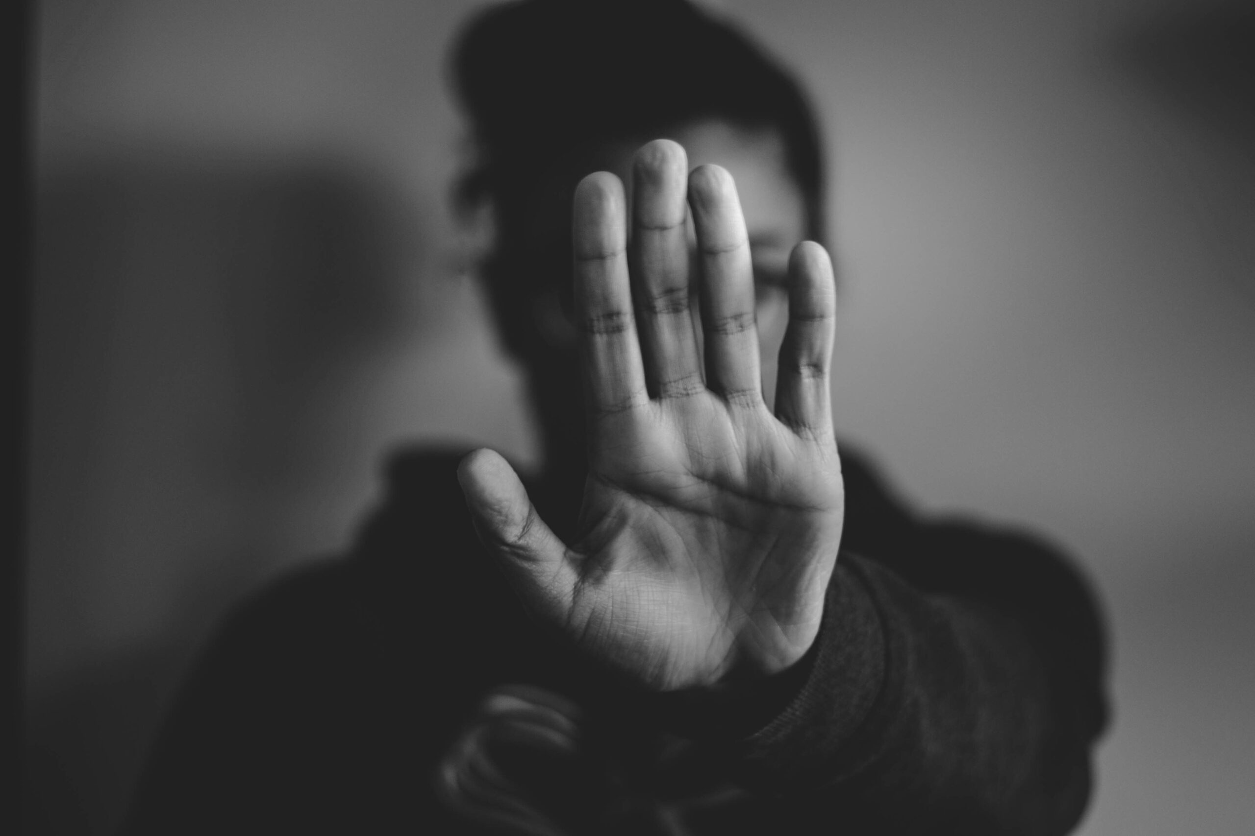 foto in b/n sfocata la mano di una donna, come segno di stop